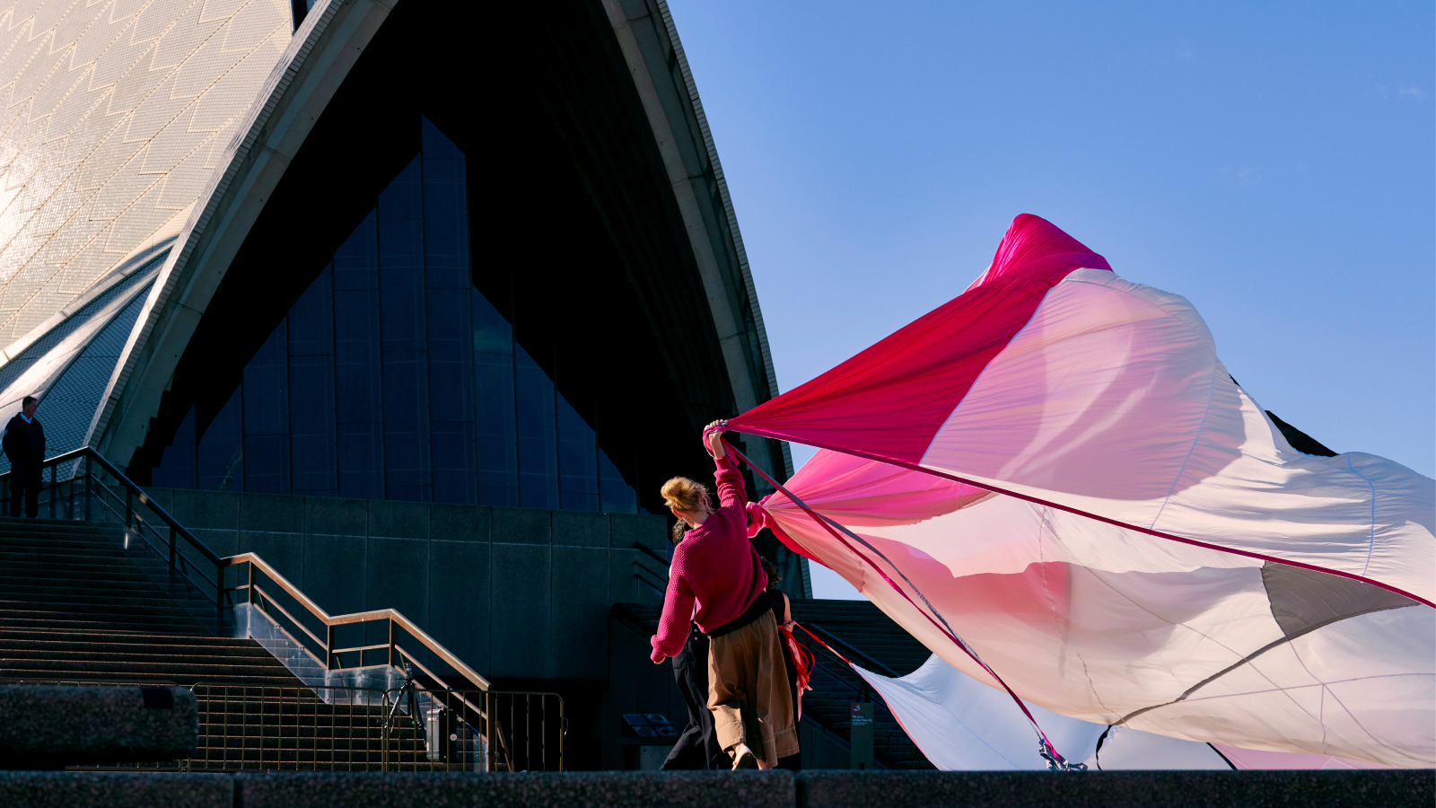 Two artists holding a big piece of cloth outside Sydney opera house.