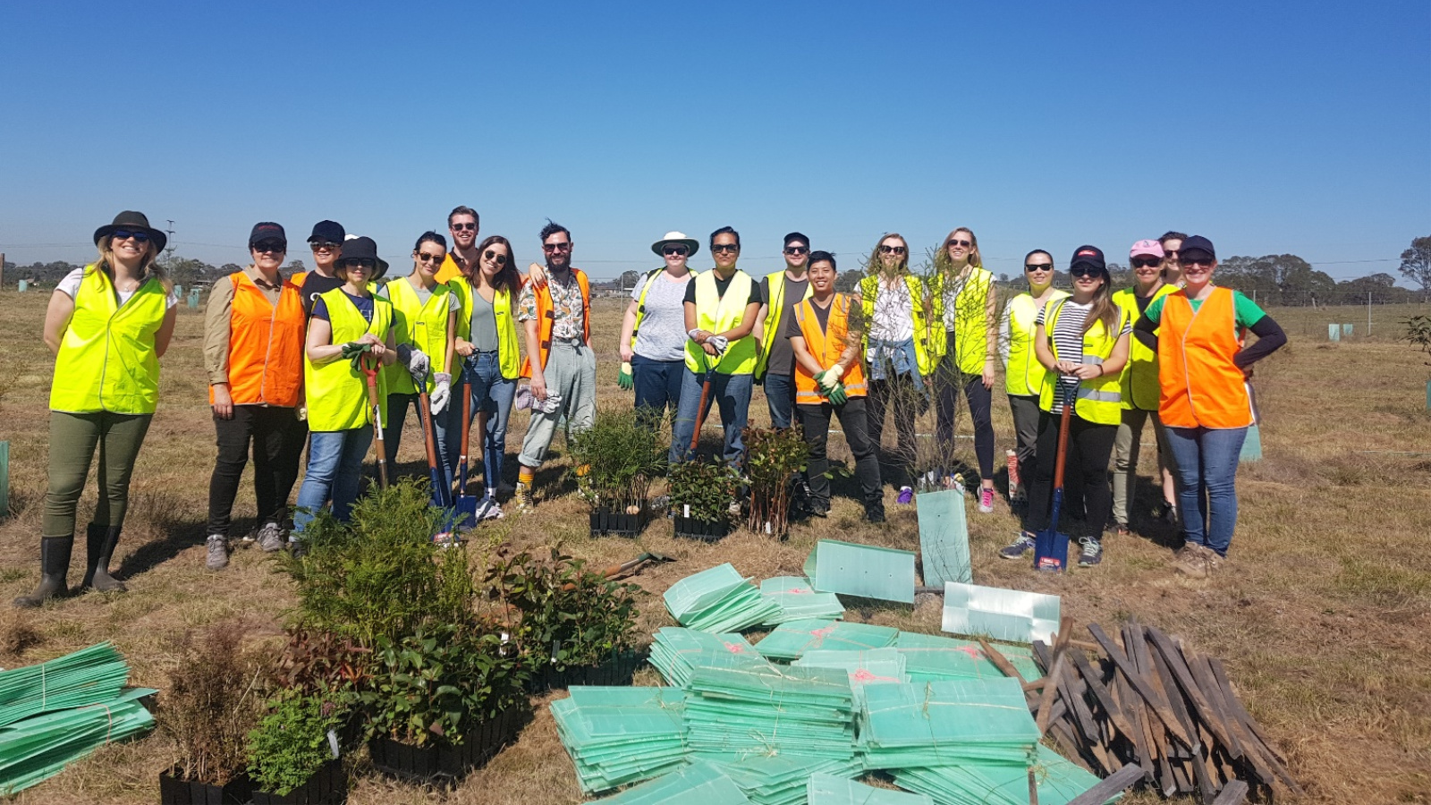 A group of people in high-vis vests and shovels.