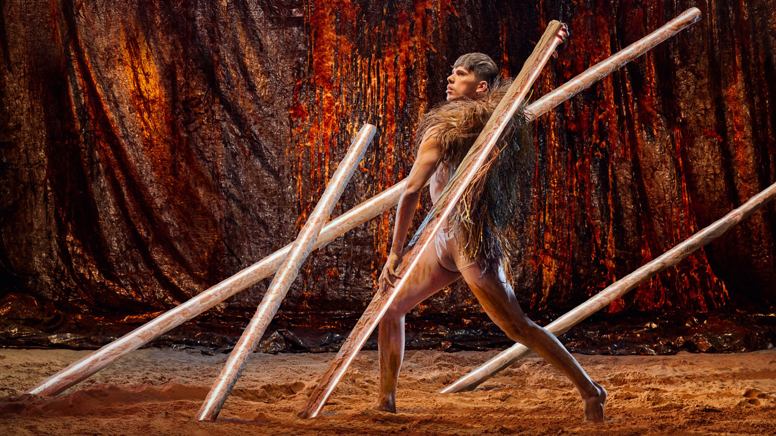 A man wearing lion skin aiming with wooden spear.