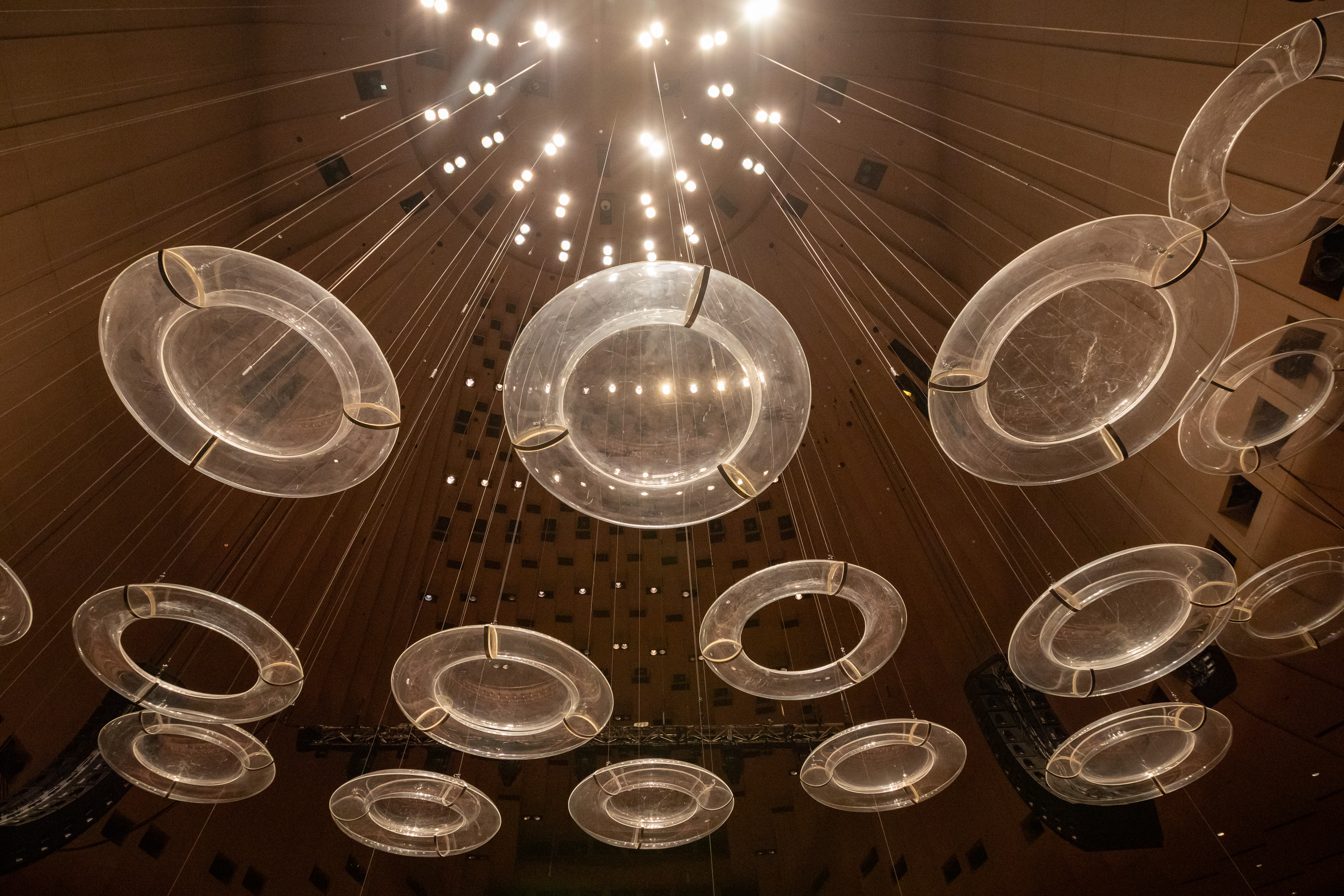 Looking up at a number of perspex discs hanging from the ceiling of the Concert Hall.
