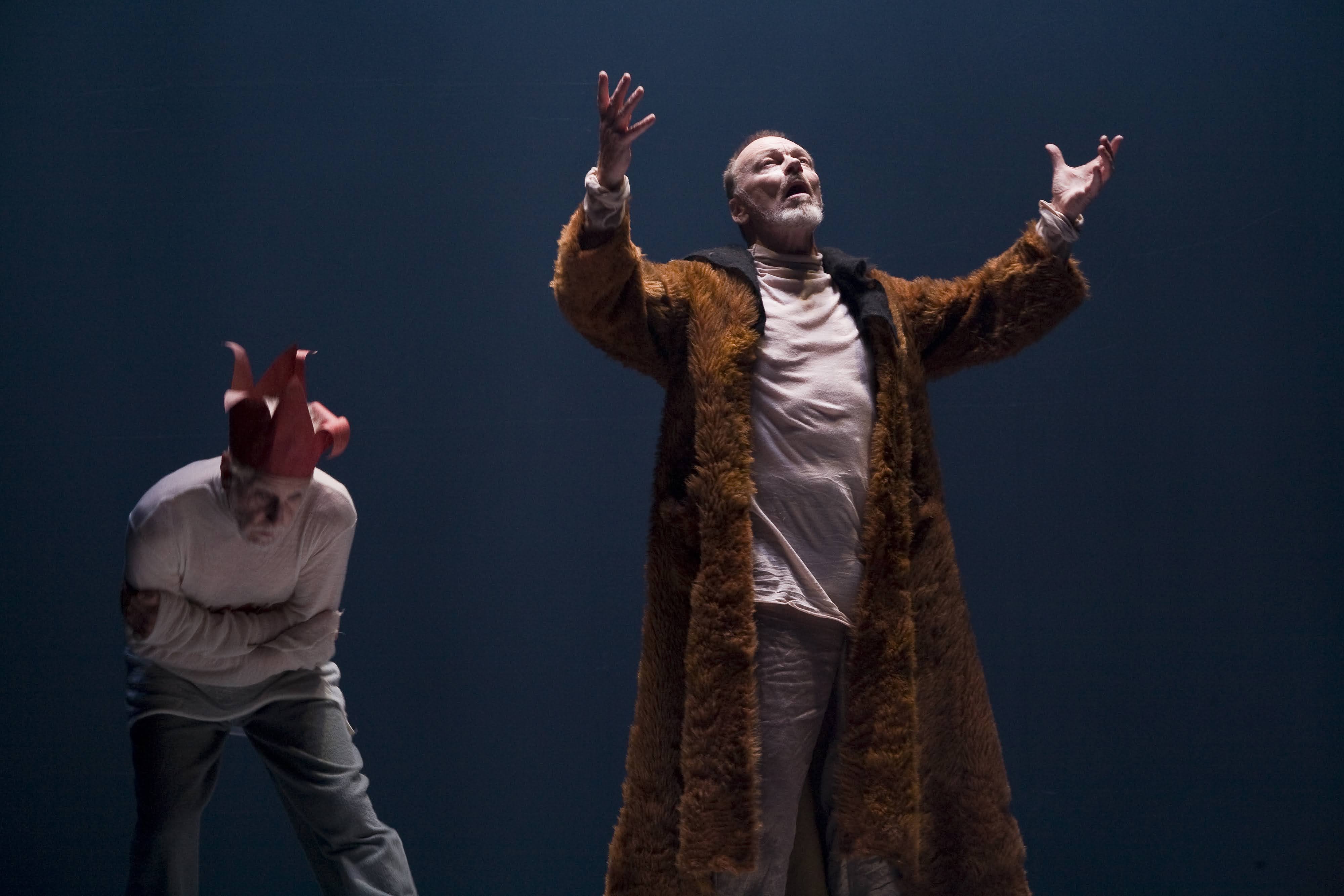 A man wearing a long coat with both hands up in the air.