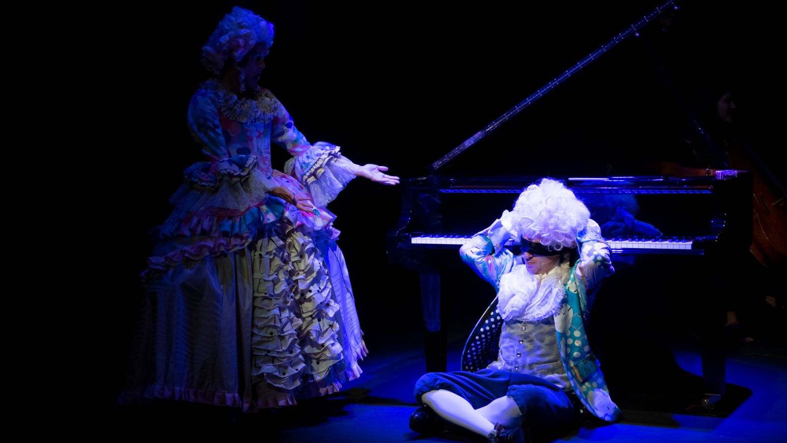 A man and woman dressed up as Mozart and his wife in colourful outfits and big white wigs