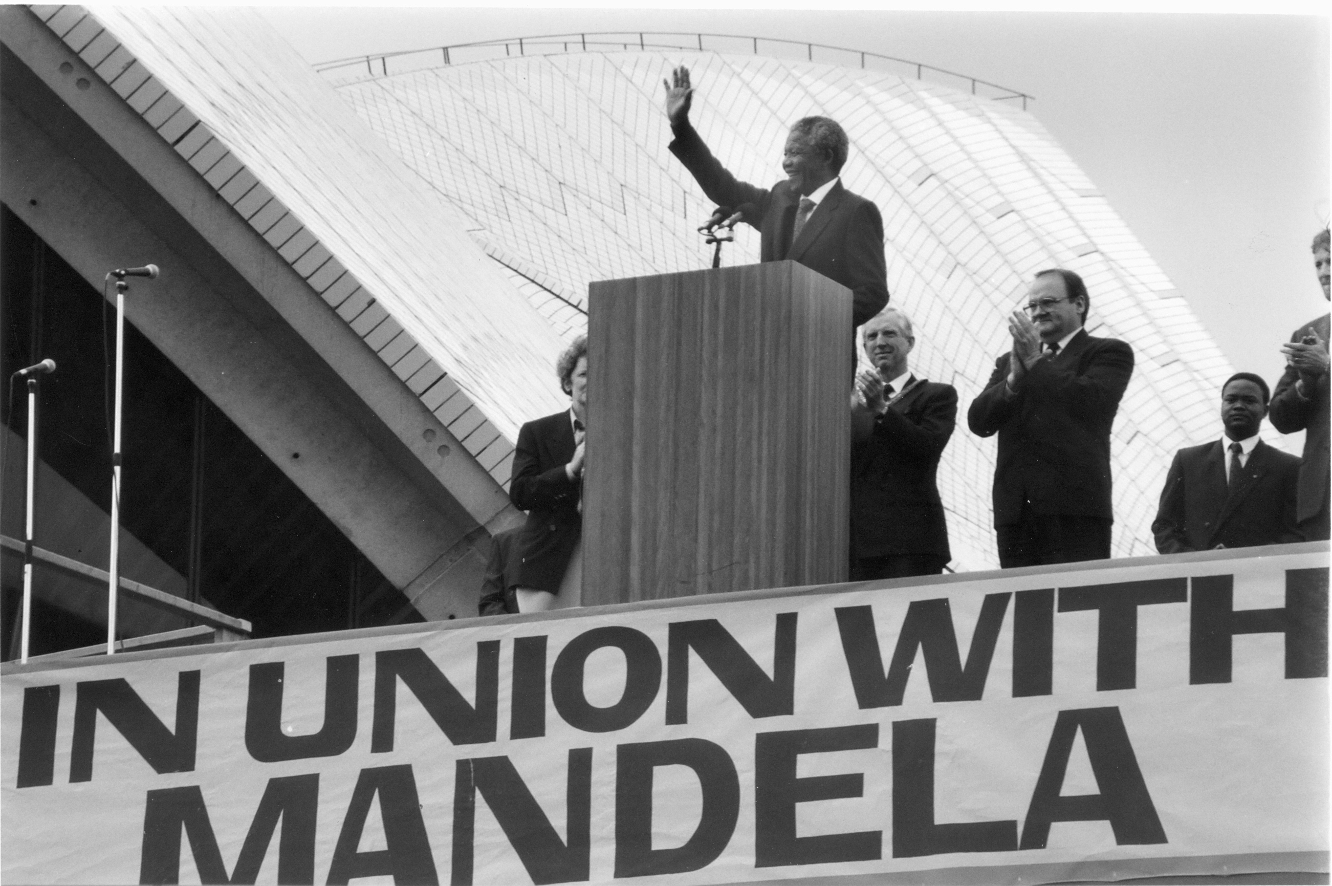 A man standing on a podium, waving his hand.