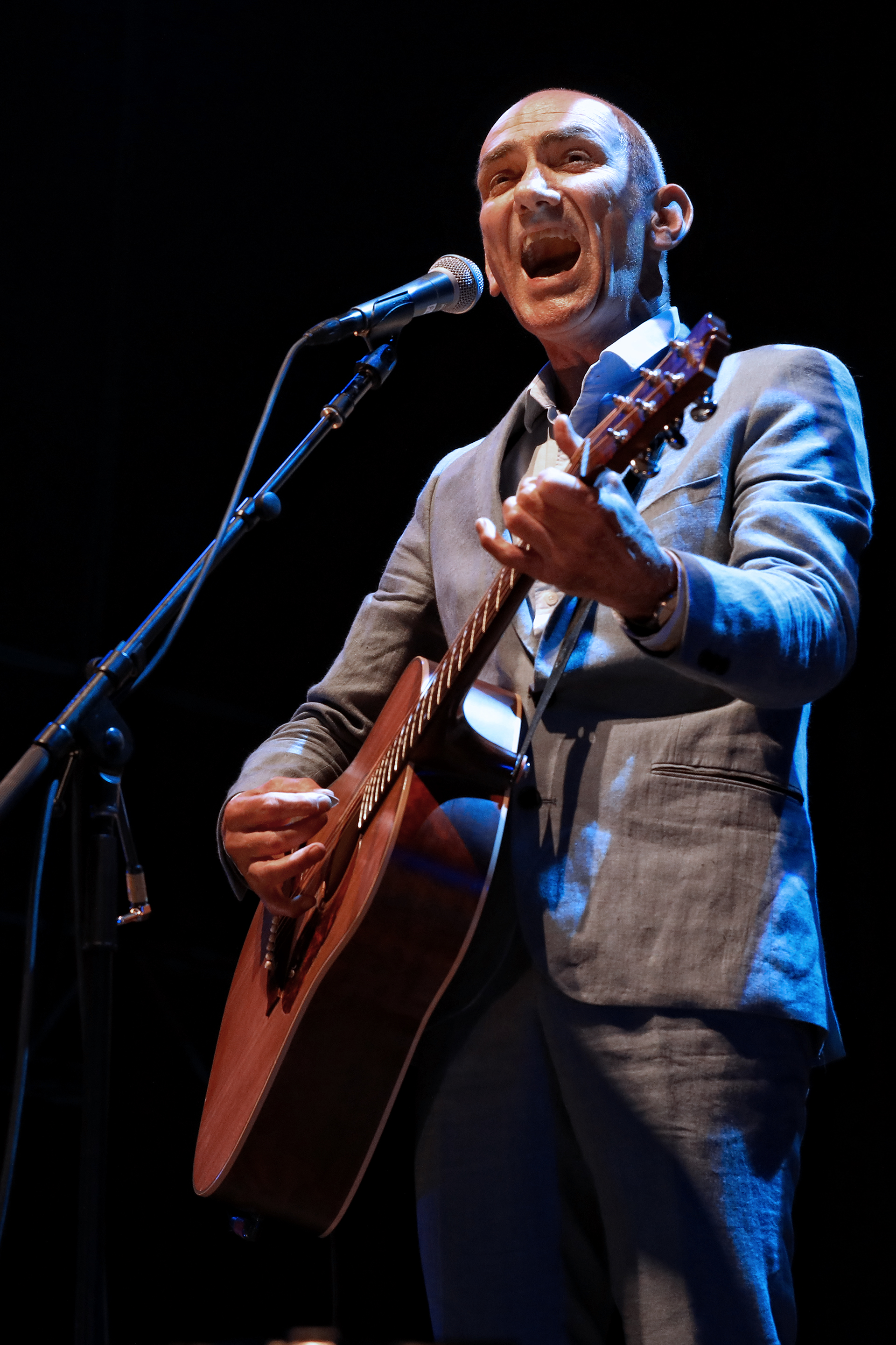 An Australian singer holding a guitar performing on the stage.