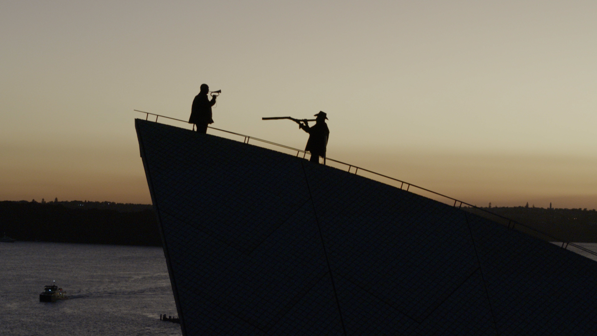 Silhouettes of a person playing a bugle and another playing the digeridoo on the sails of the Opera House.