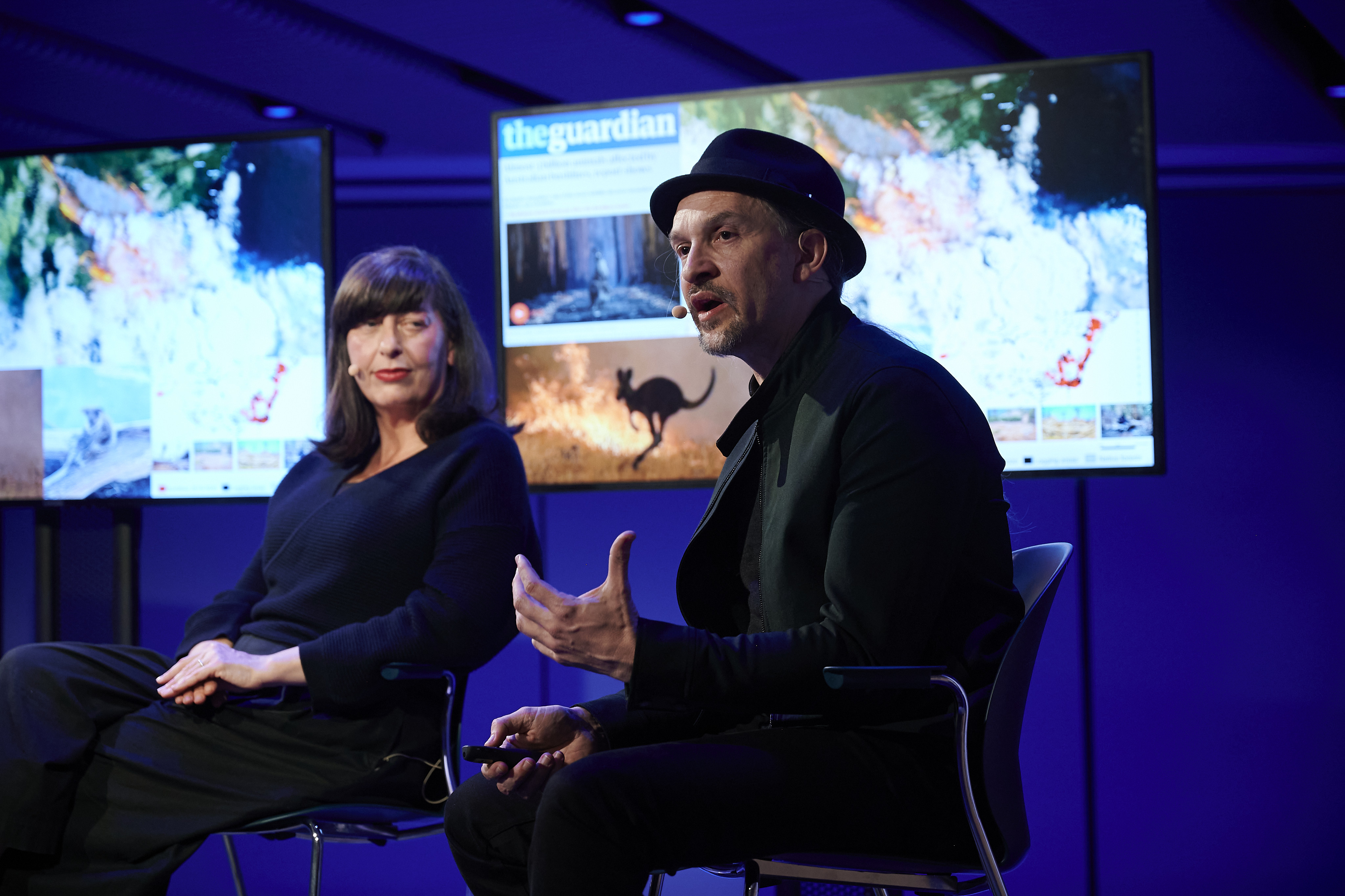 A man and a woman sitting on a chair in a talk show.