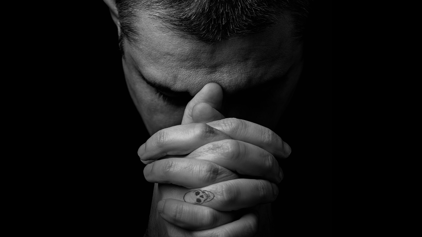 A man resting his forehead on his hands.