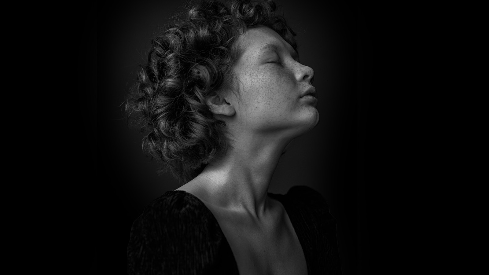 A woman with curly hairs and speckle on the face.