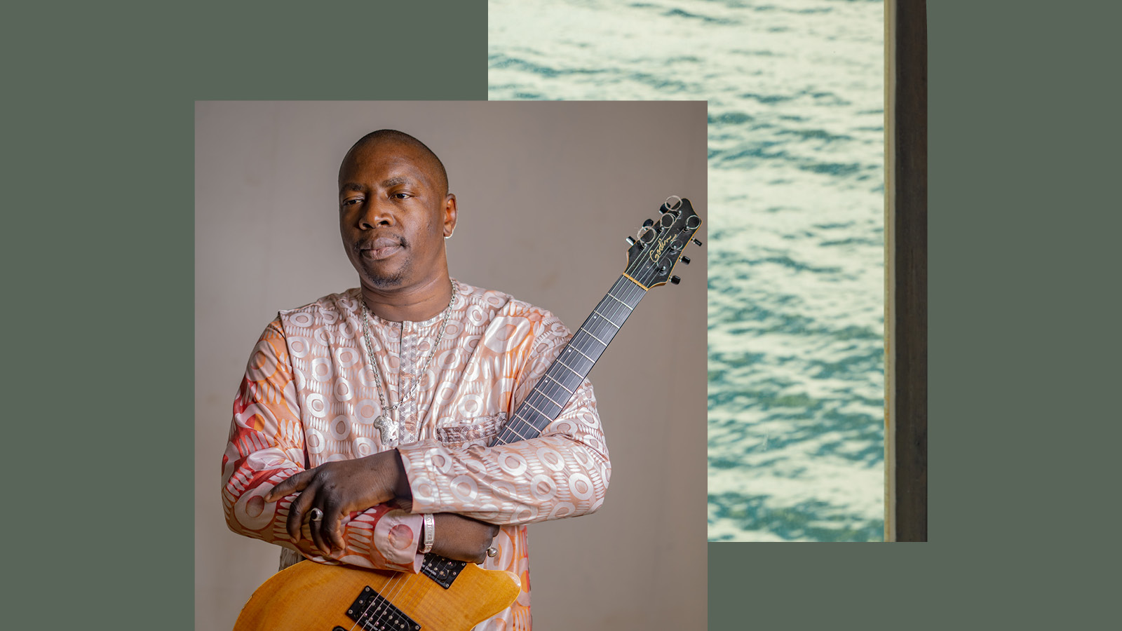 Vieux Quartet Toure a Malian singer in traditional wear holding his guitar.