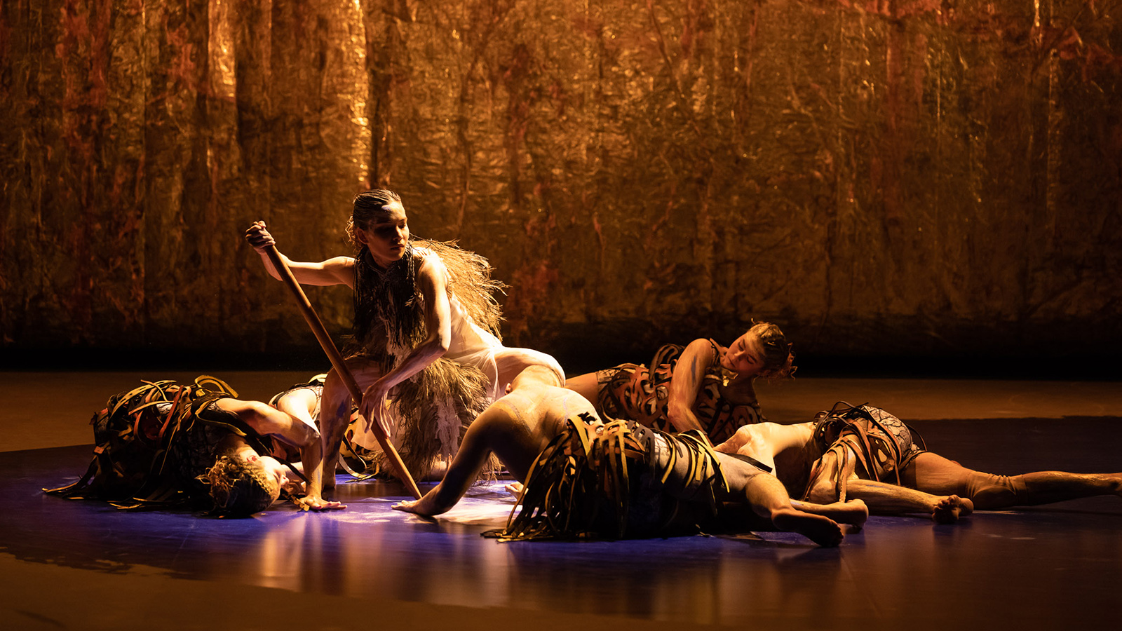 A group of dancers performing a traditional Aboriginal dance on a stage.