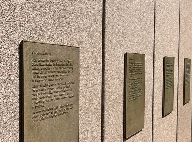 A row of plaques with raised text on a wall.