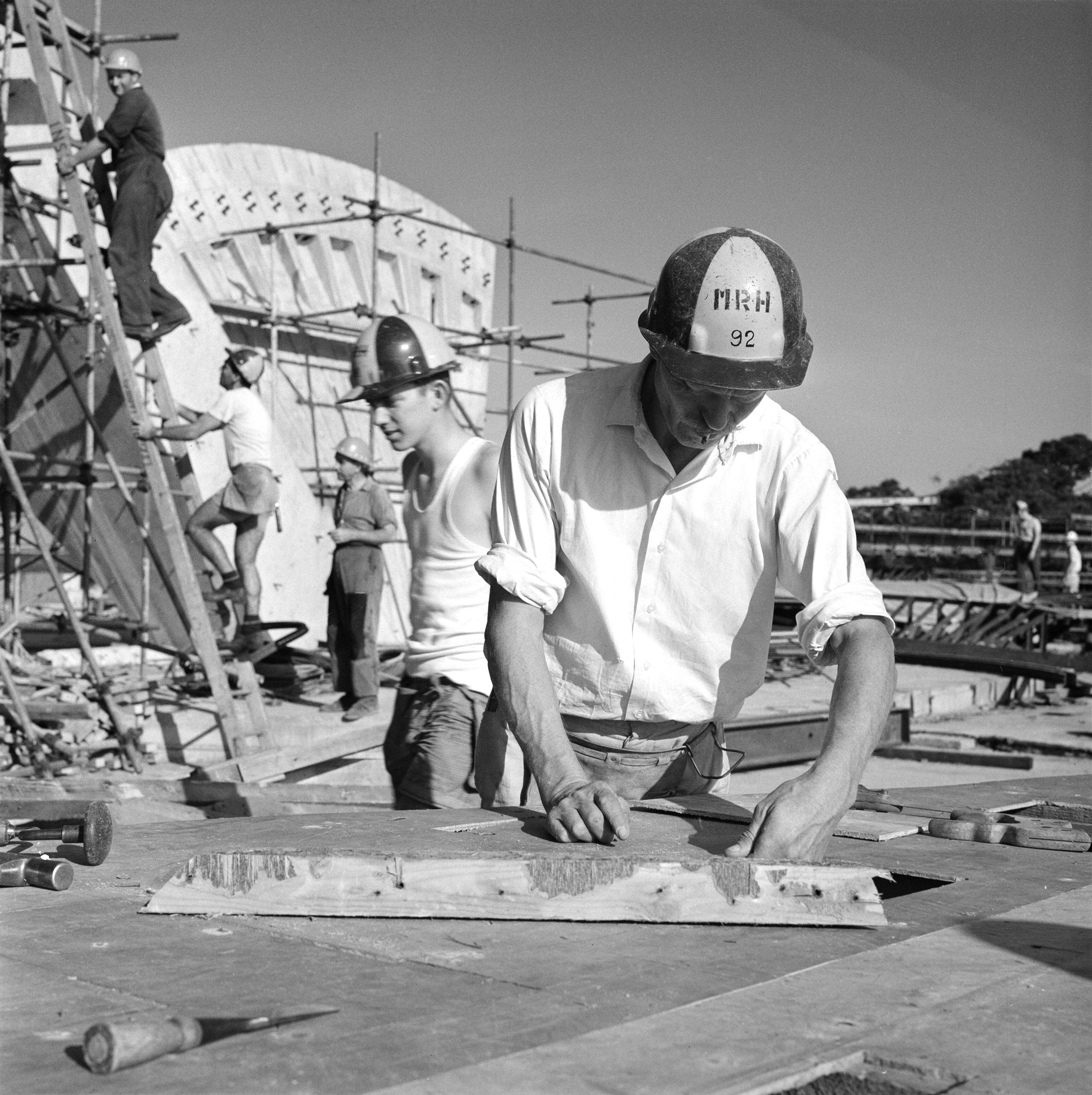 A group of five people in hard hats working on the construction site of the Sydney Opera House.