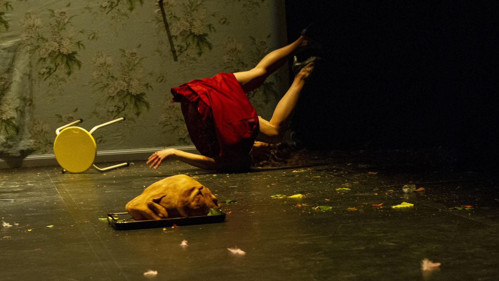 A chaotic scene with a lady blown upside down by strong winds. She wears a red dress with her legs in the air. Debris in scattered all around her.