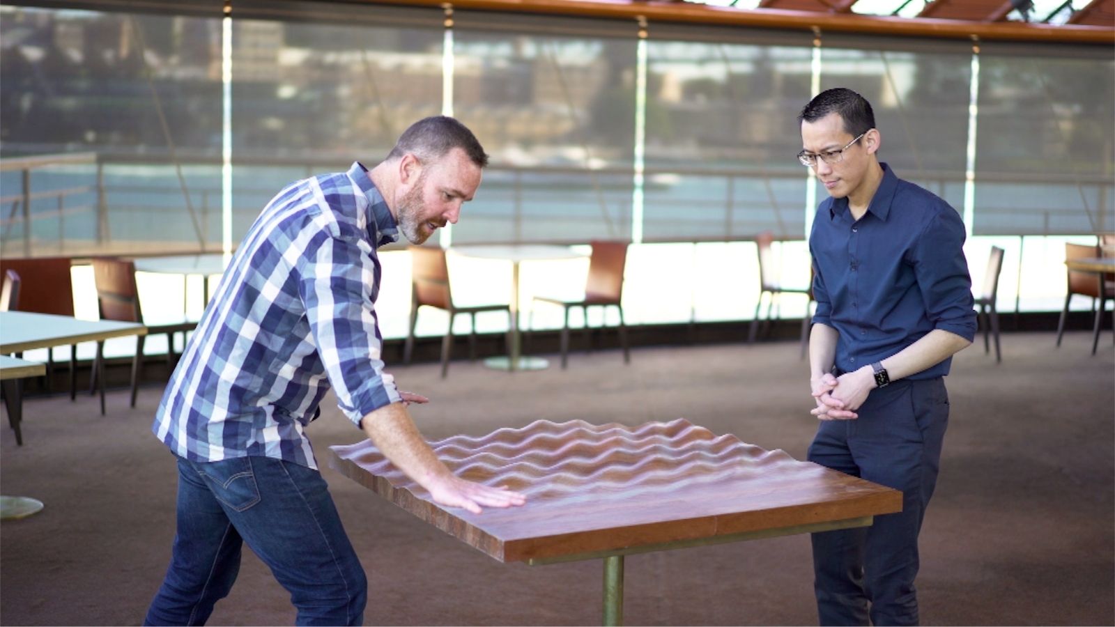 Two men standing looking over a table.