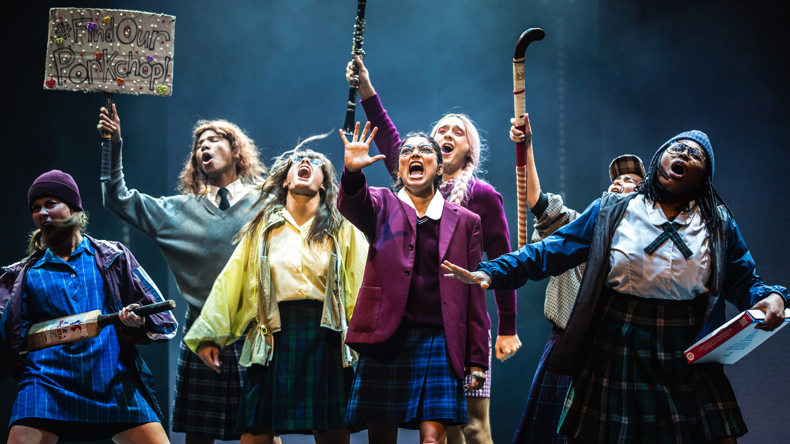 A group of girls with hockey sticks dancing on stage.