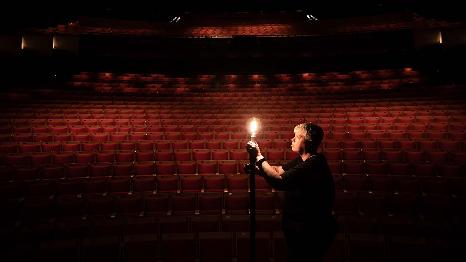 Person holding up a light in front of an empty theatre.