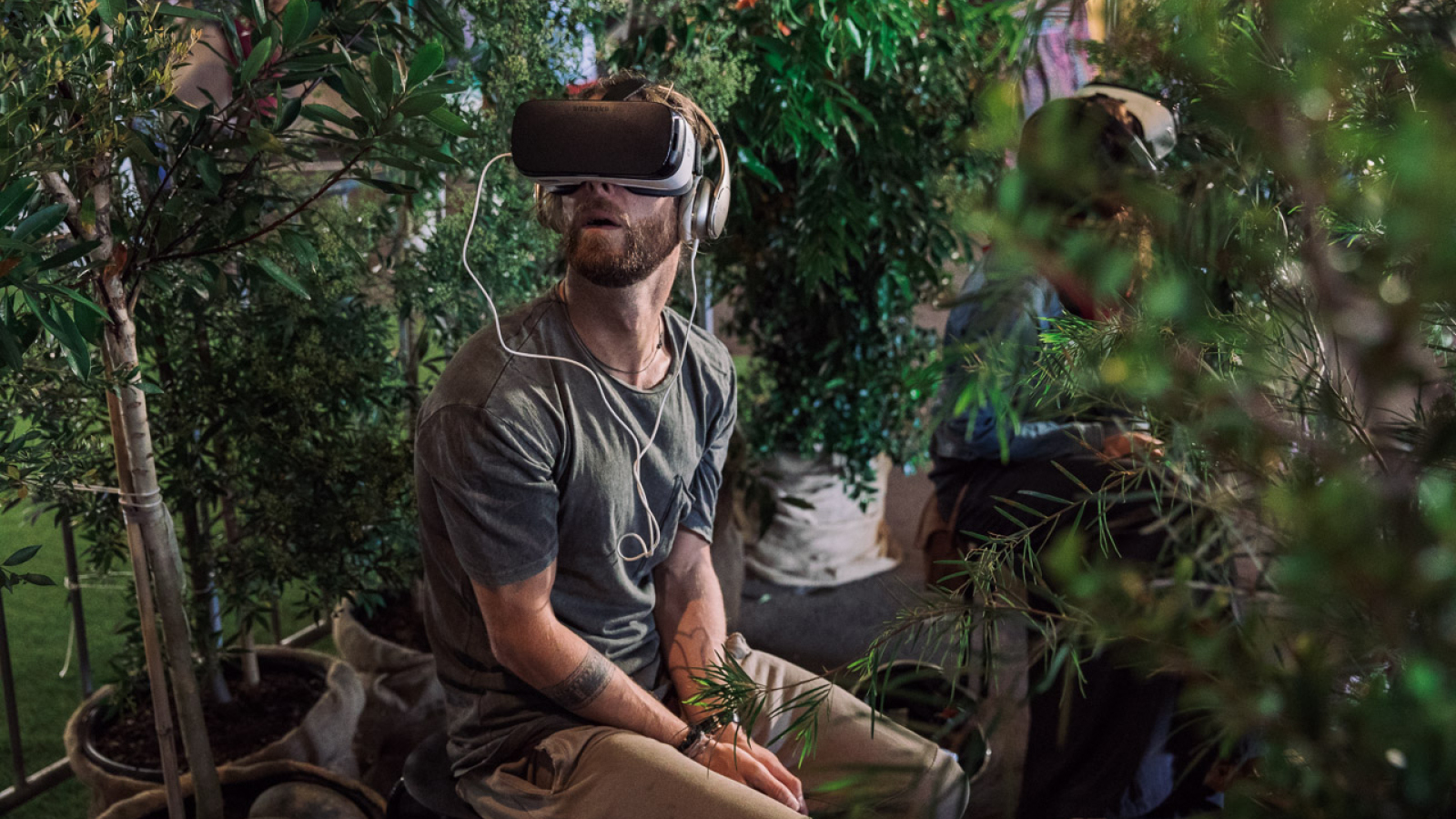 A man sitting in a plant nursery wearing a VR set.