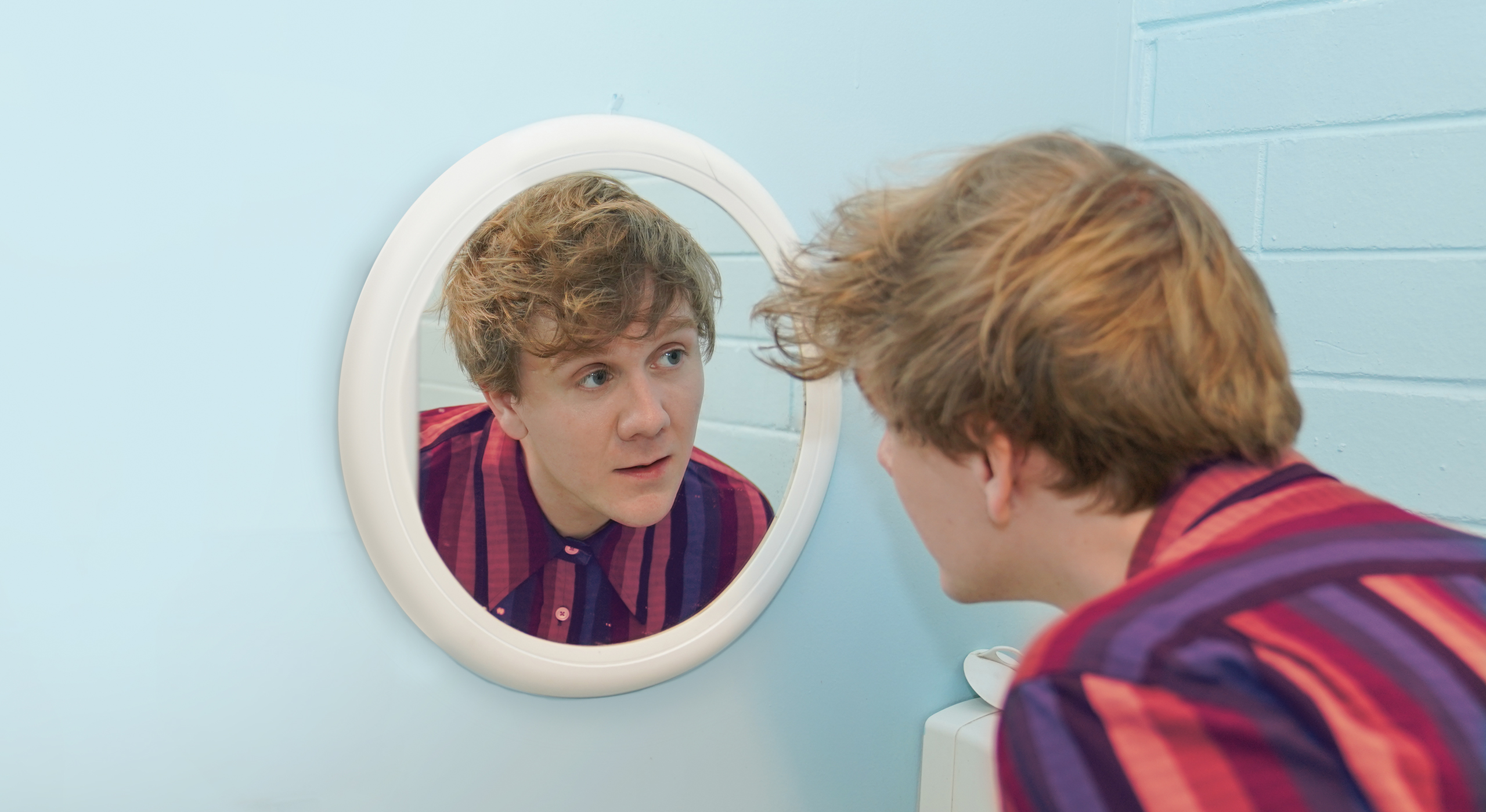 Josh Thomas staring into a mirror