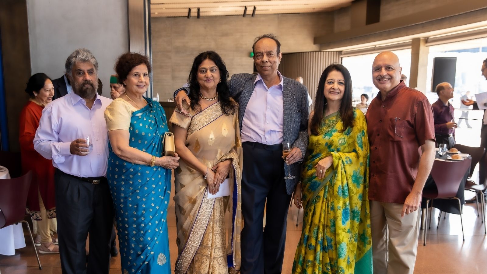A group of people dressed in saris and suits, gathered for a photo.