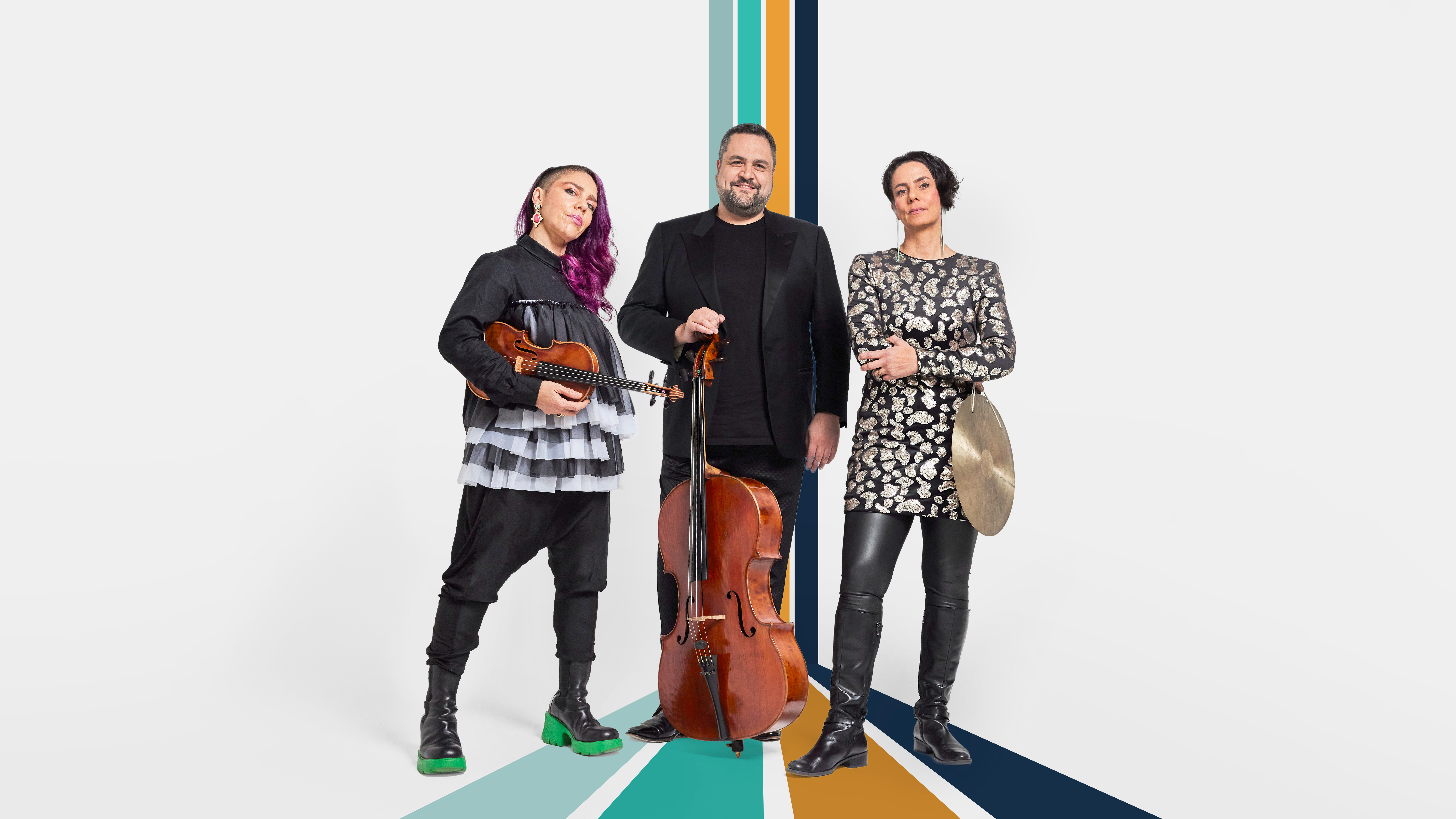 Two women and one man pose for a picture holding a violin, cello and cymbol.