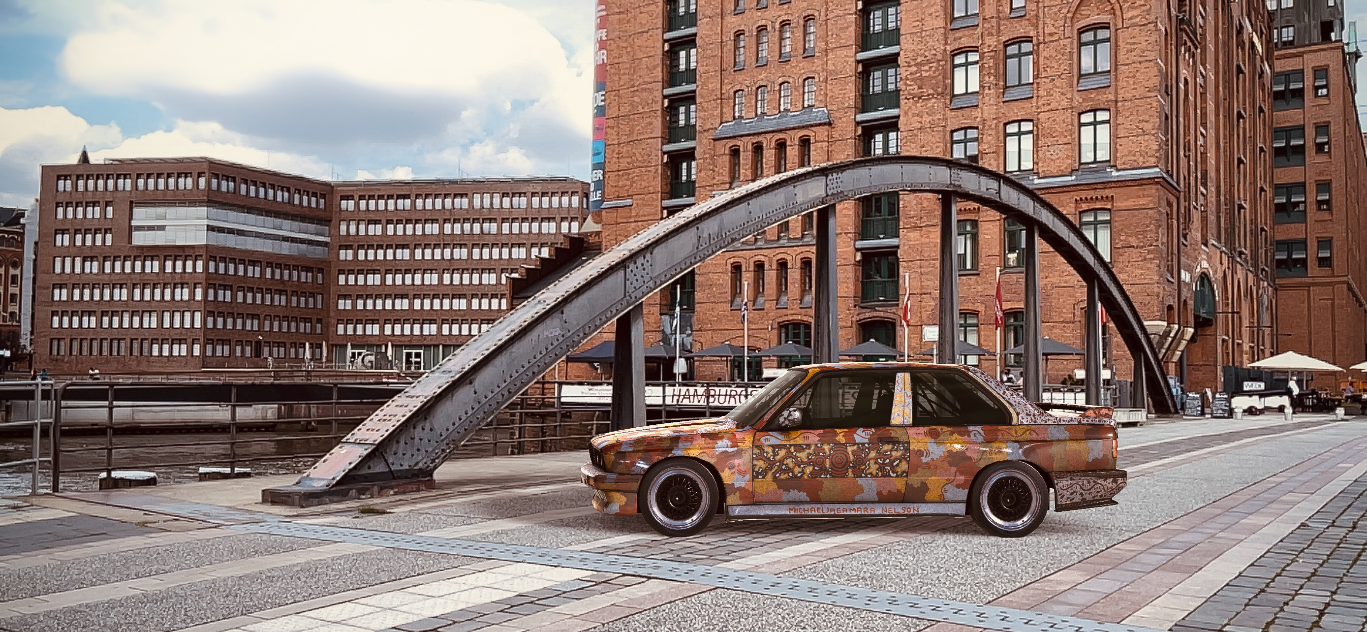 A BMW sedan covered in patterns of ochre, yellow, brown and blue parked on the pavement in front of high-rise buildings.