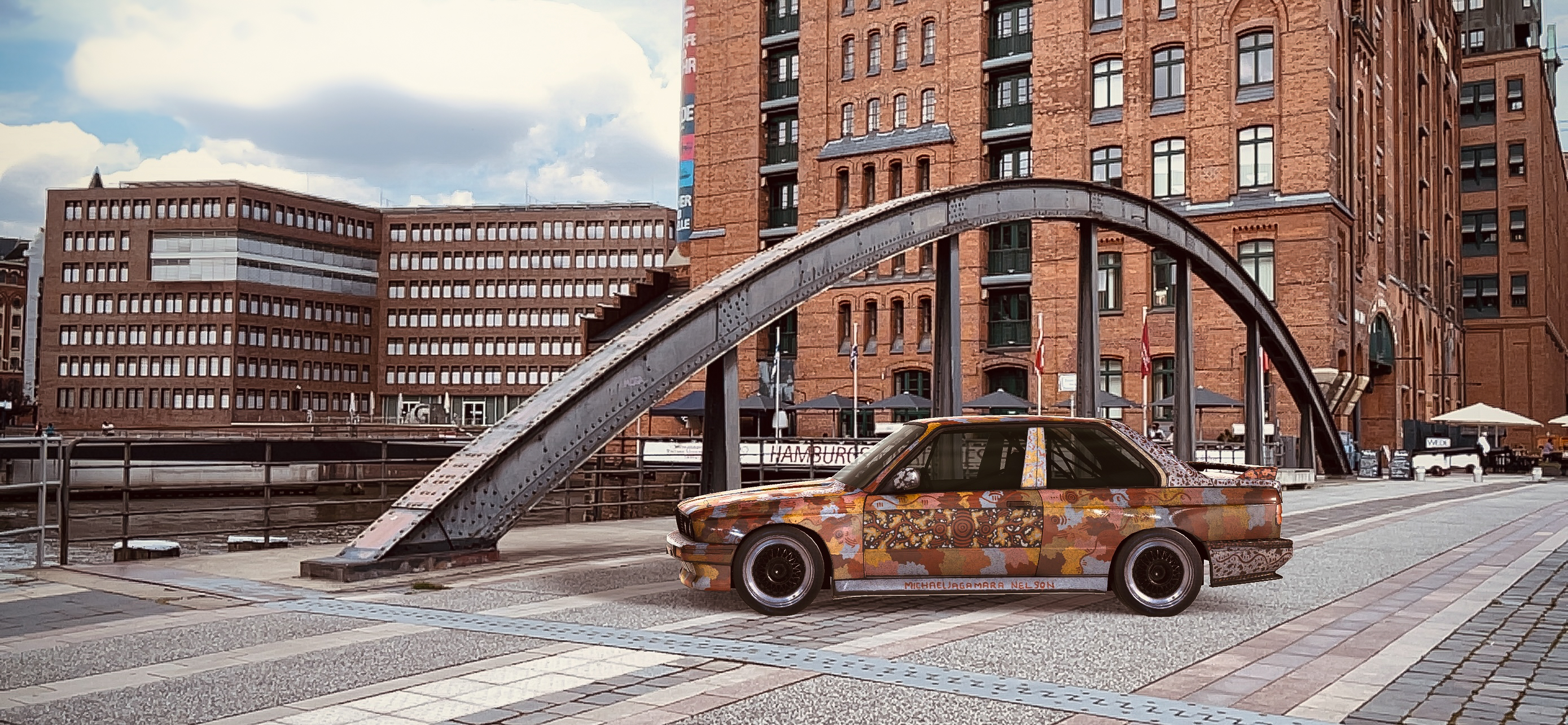 A BMW sedan covered in patterns of ochre, yellow, brown and blue parked on the pavement in front of high-rise buildings.