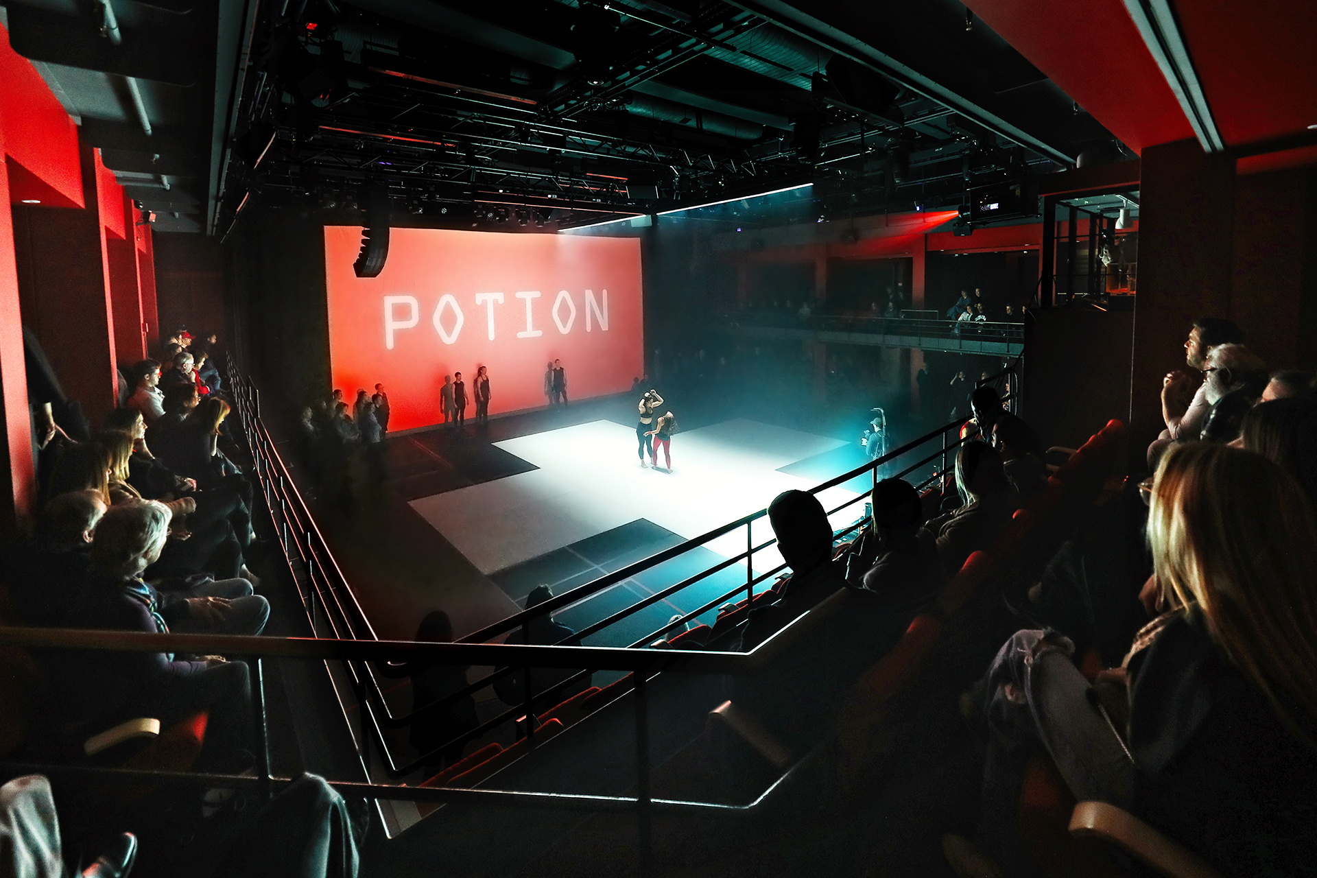 Audience watching performers on stage under lights