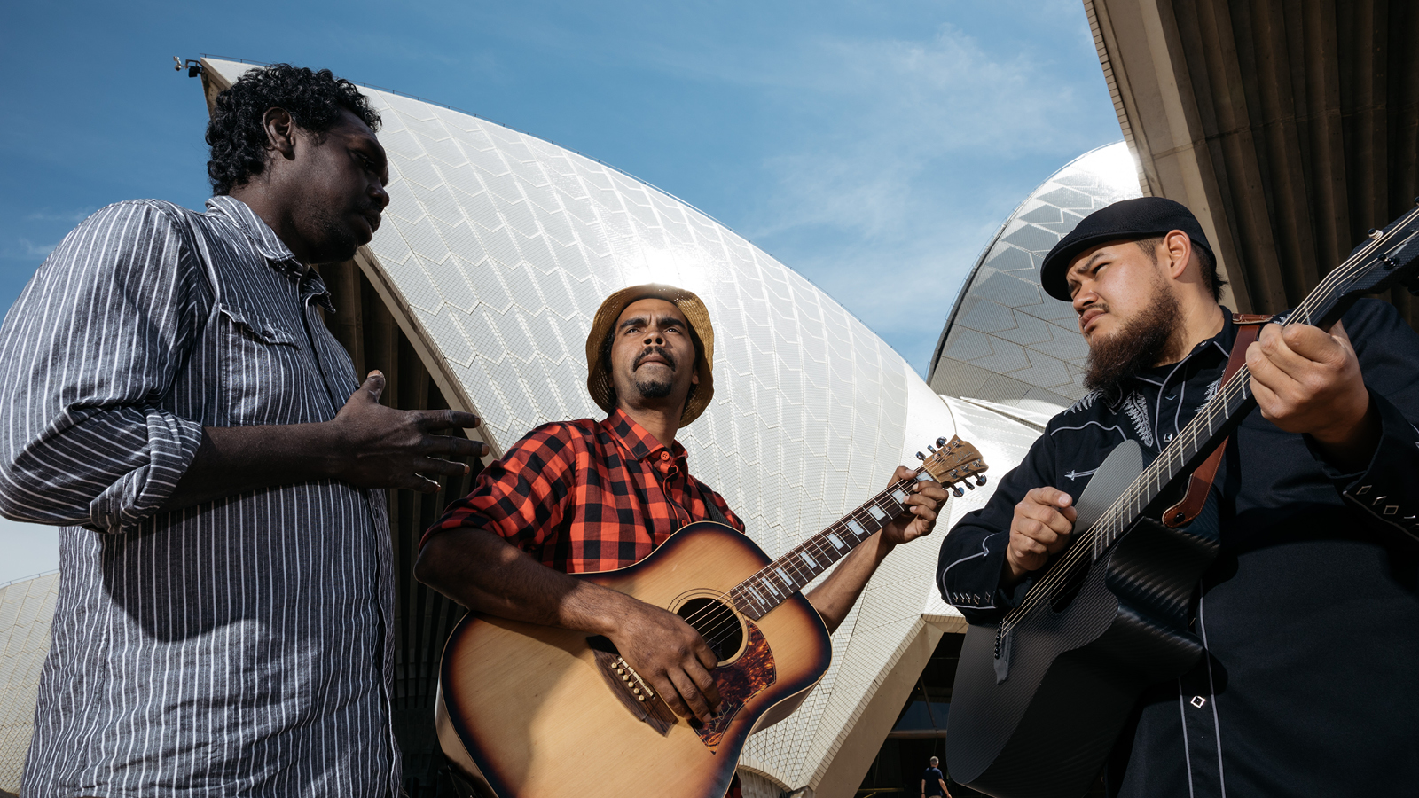 Two men holding a guitar and one man standing next to them.