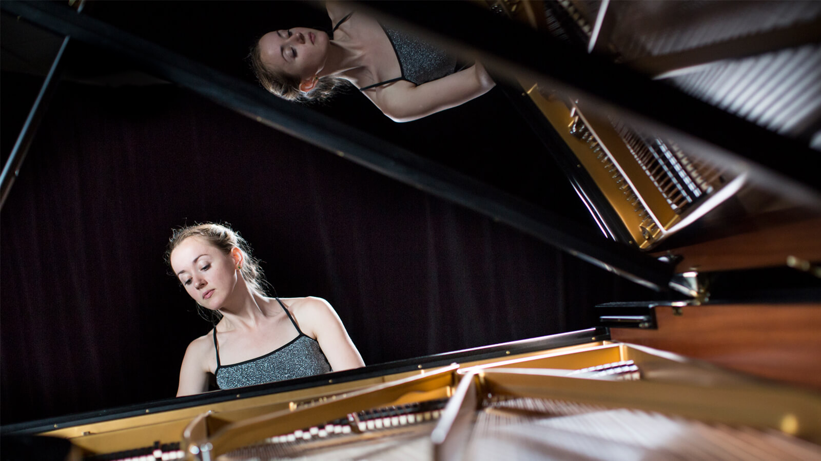 A blonde woman playing a grand piano.