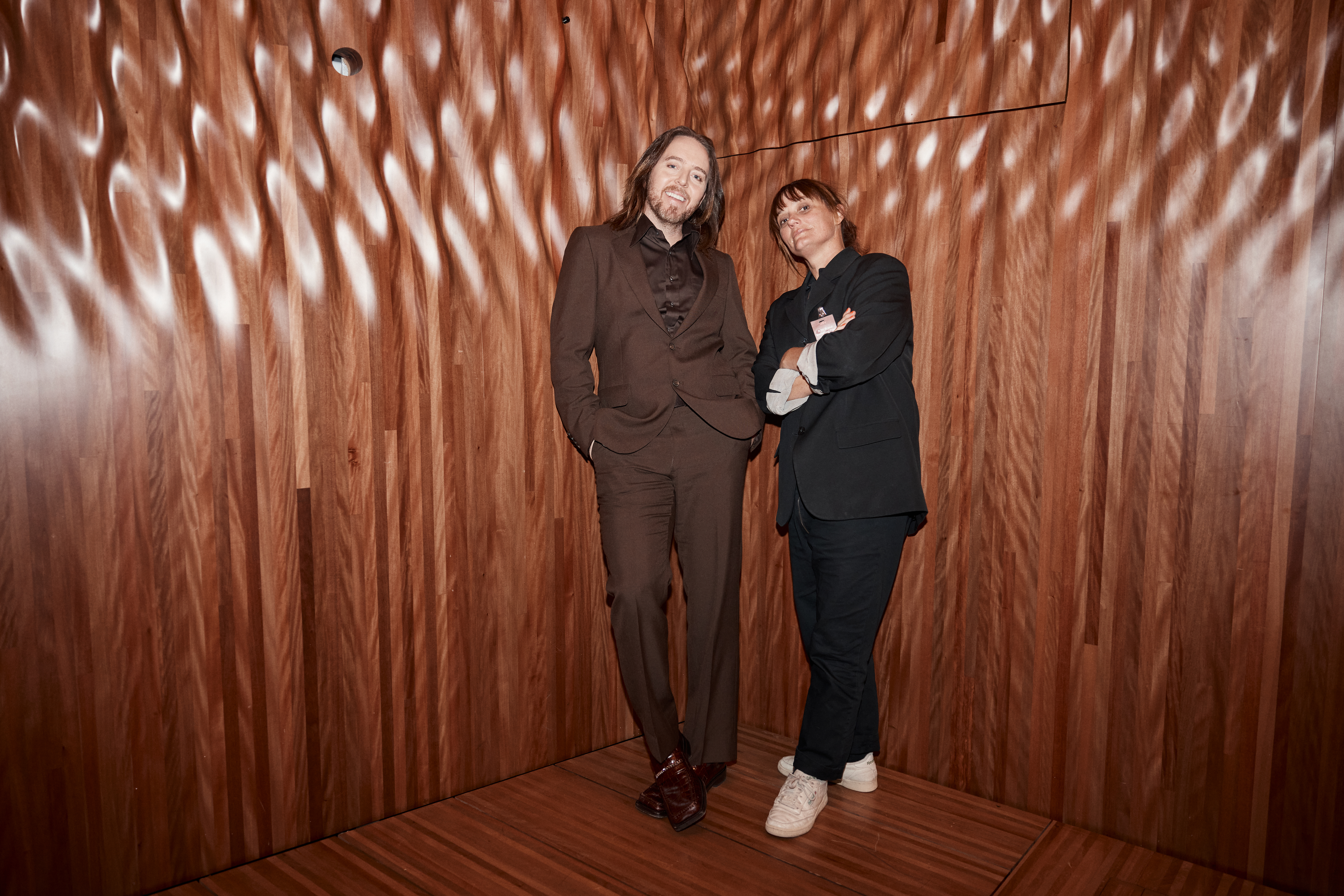 Tim Minchin and Kim Gehrig standing together against a wall inside the Opera House.