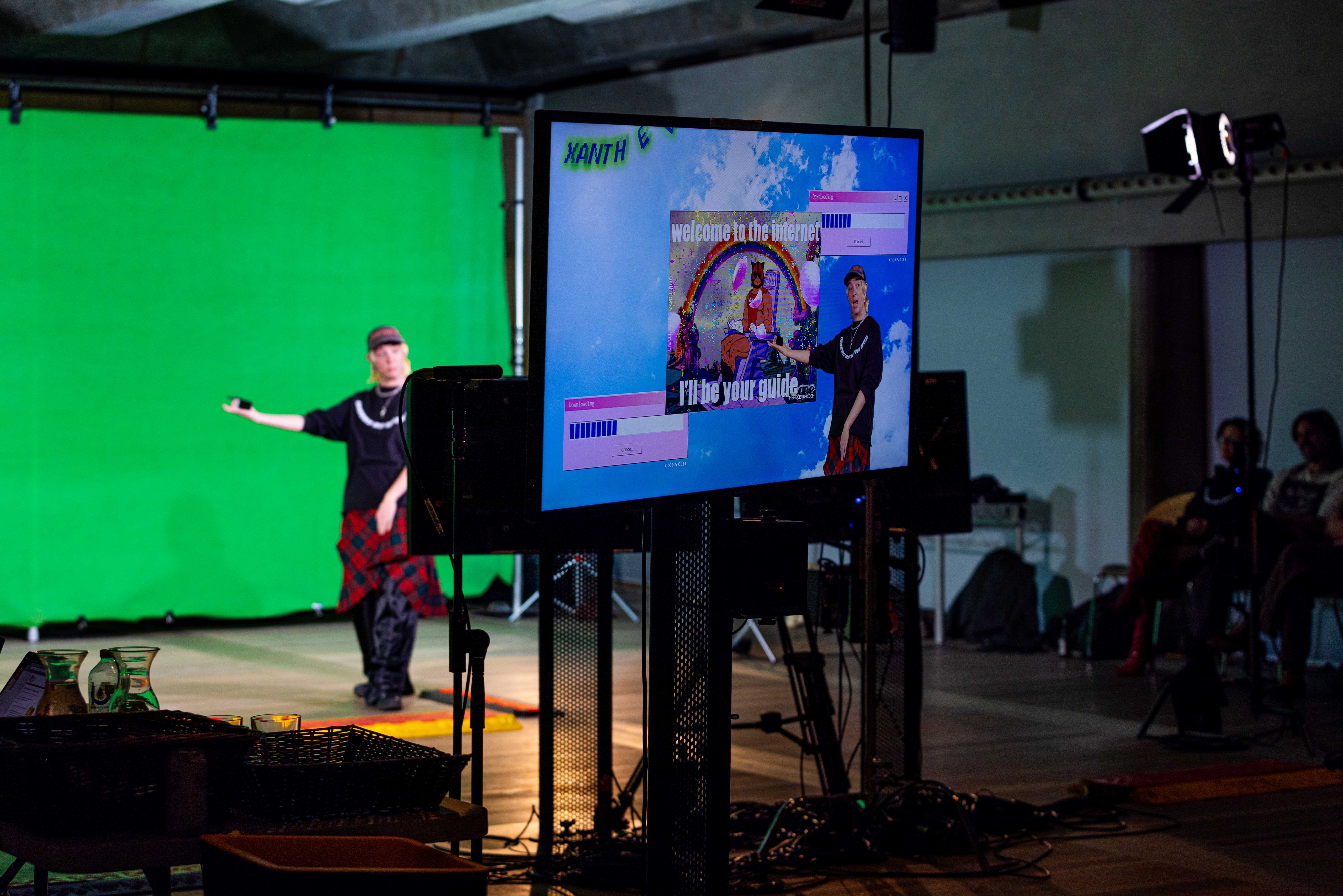 Producer's view through a screen showing a digital background, of a performer in front of a green screen
