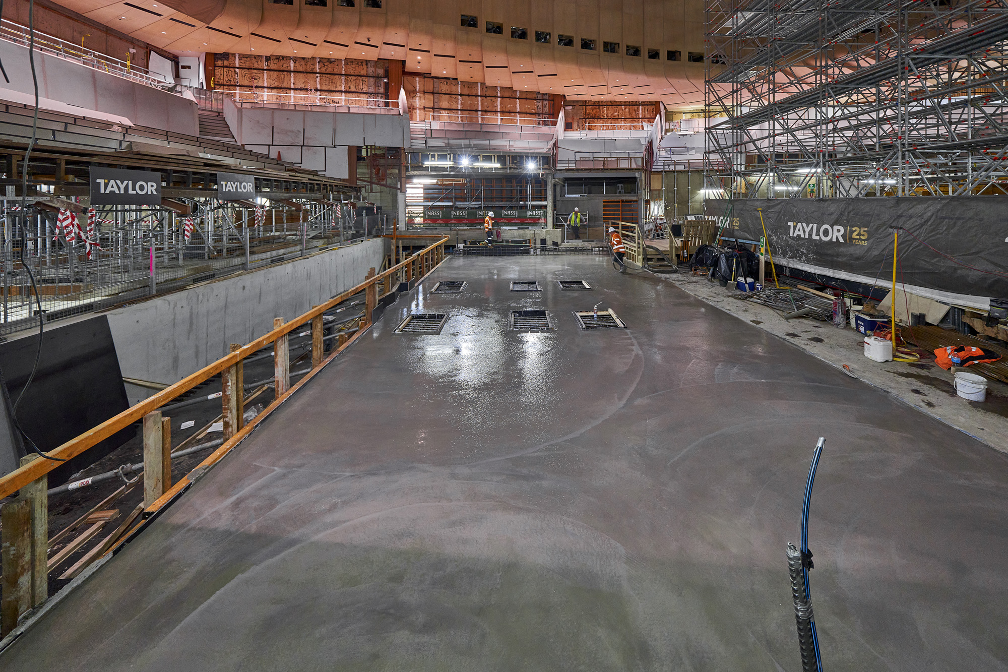 Construction workers pouring concrete into the new steel frame of the stage.