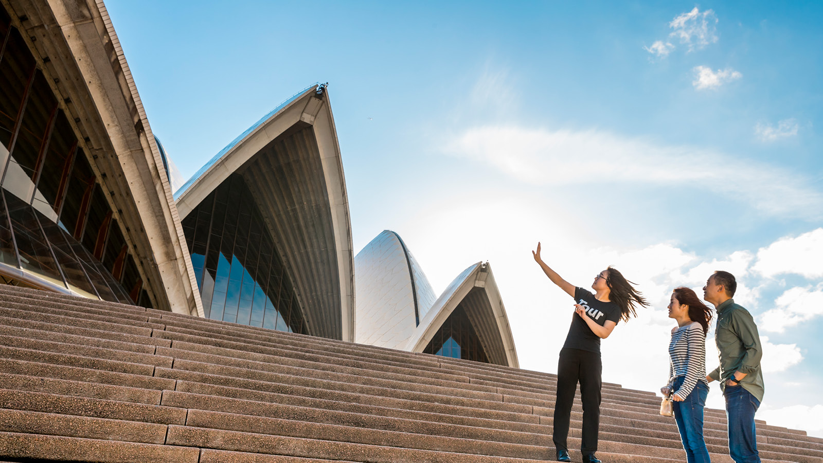 A tour guide outside Sydney opera house with a couple.