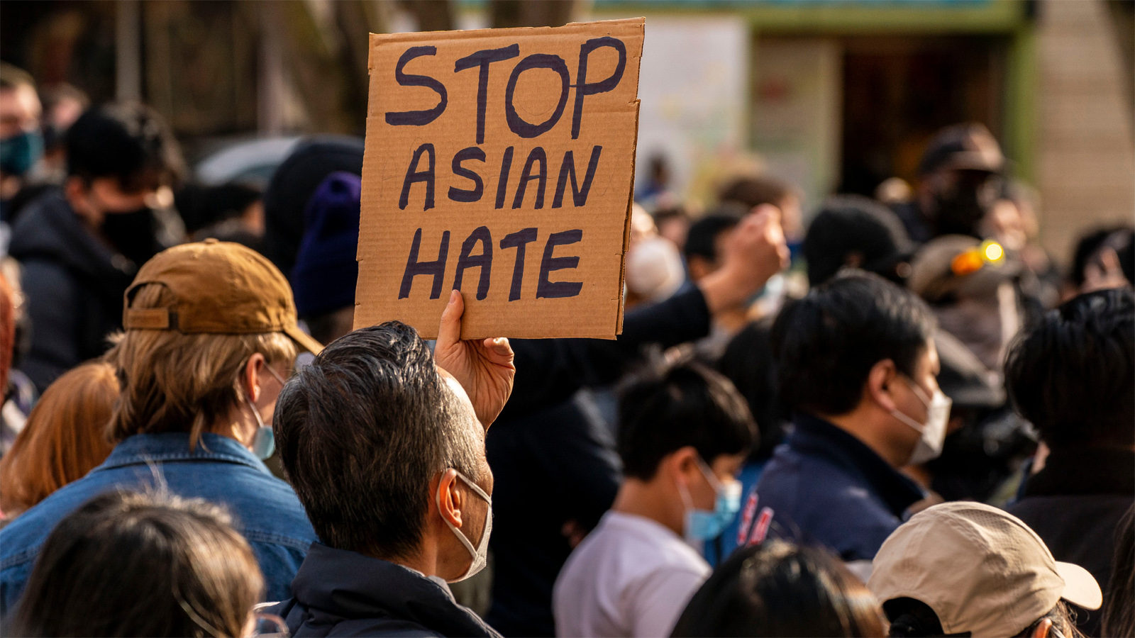 A crowd of people in masks with a sign titled 'Stop Asian Hate'.