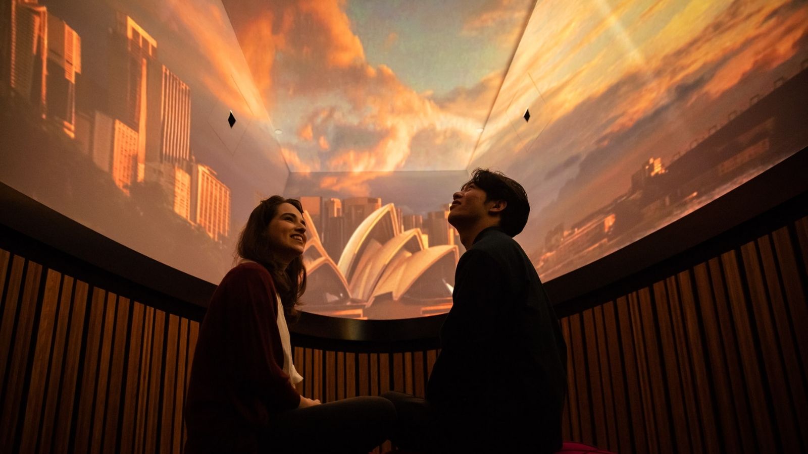 A couple in a room watching a show projection on the ceiling.