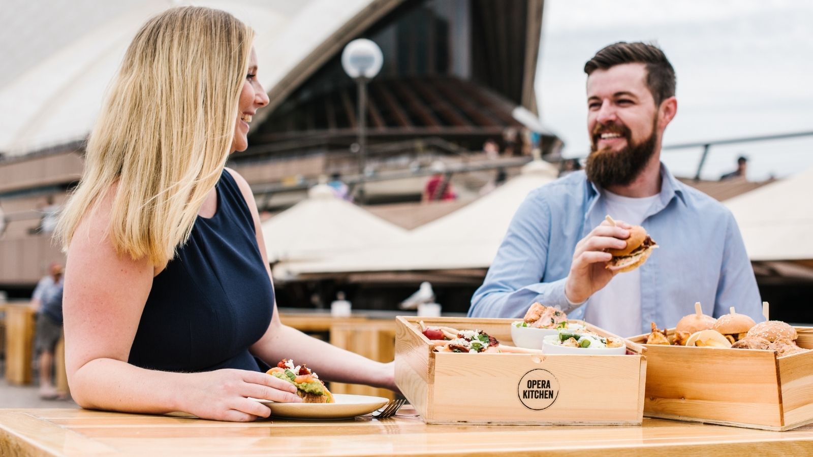 A man and a woman having burger sliders.