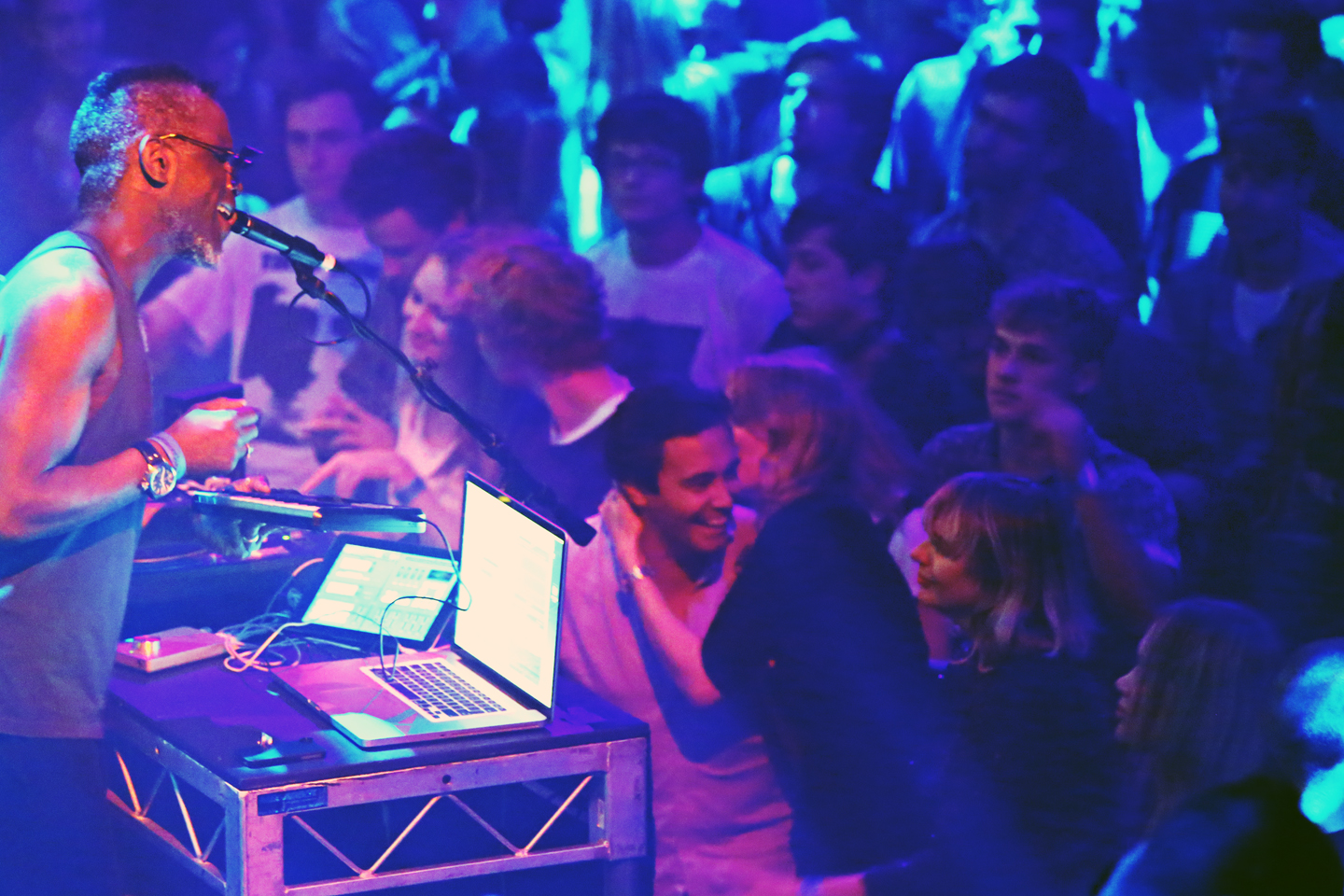 A DJ performing on stage to a lively audience.