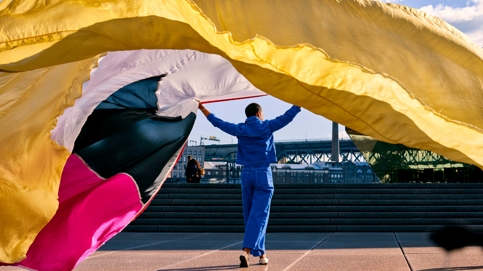 A man holding a long colourful curtain.