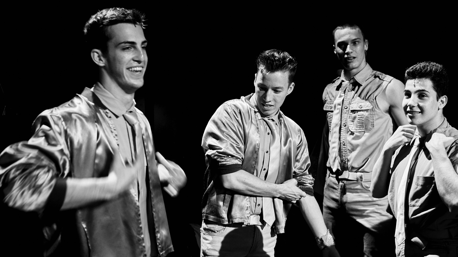 A group of four young men with slicked back hair, smiling.