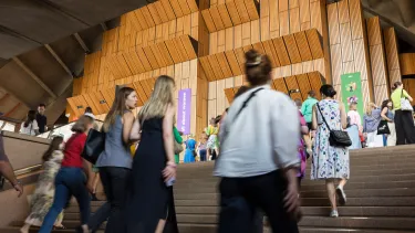 Women walk up the Sydney Opera House concert hall stairs.