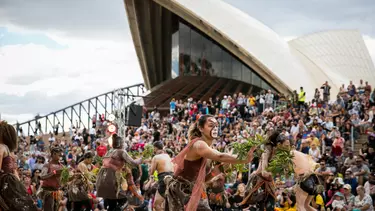 Women in sand pit performing indigenous dance in the Homeground of Sydney opera house.