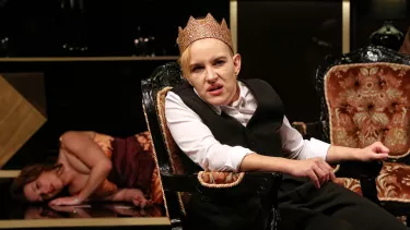 A woman with a crown on, seated.