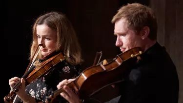 A closeup of two violin players side by side