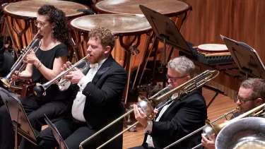 Brass section of the Sydney Symphony Orchestra play in front of the Timpani and percussion section