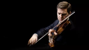 James Ehnes plays the violin in front of a black background