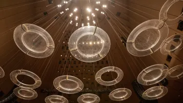 Looking up at a number of perspex discs hanging from the ceiling of the Concert Hall.