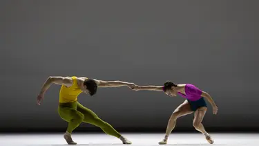 A male dancer with a female dancer, both in dynamic poses on a stage.
