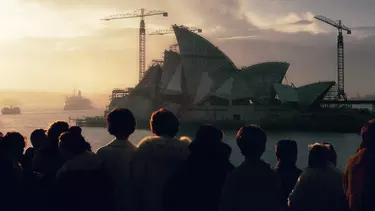 A group of people looking over the water at the Sydney Opera House getting built.
