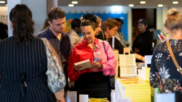 A man and a woman carefully look at a book.