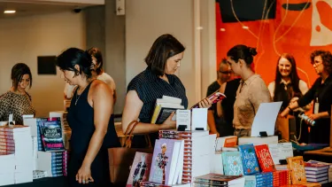 Women browse a selection of books in the Western Foyers lobby.